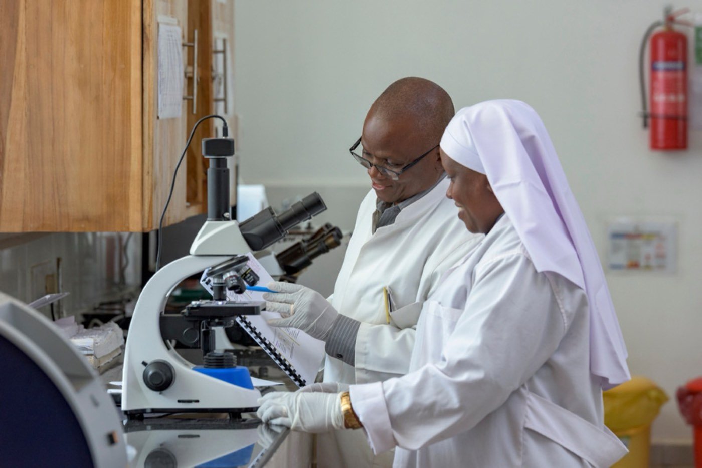 A laboratory scientist and a religious sister at a microscope
