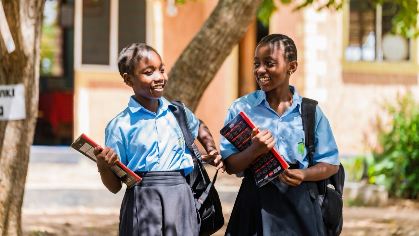 Two secondary school students smiling with textbooks
